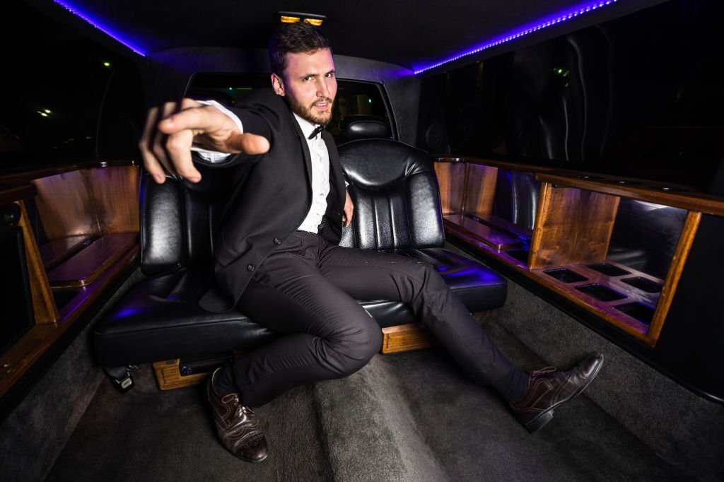 A man sits in the back of a limousine,